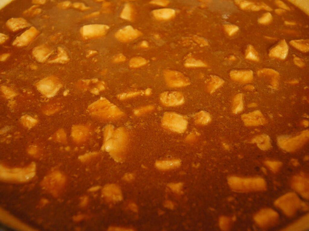 Image shows sauce with chicken in the pan.