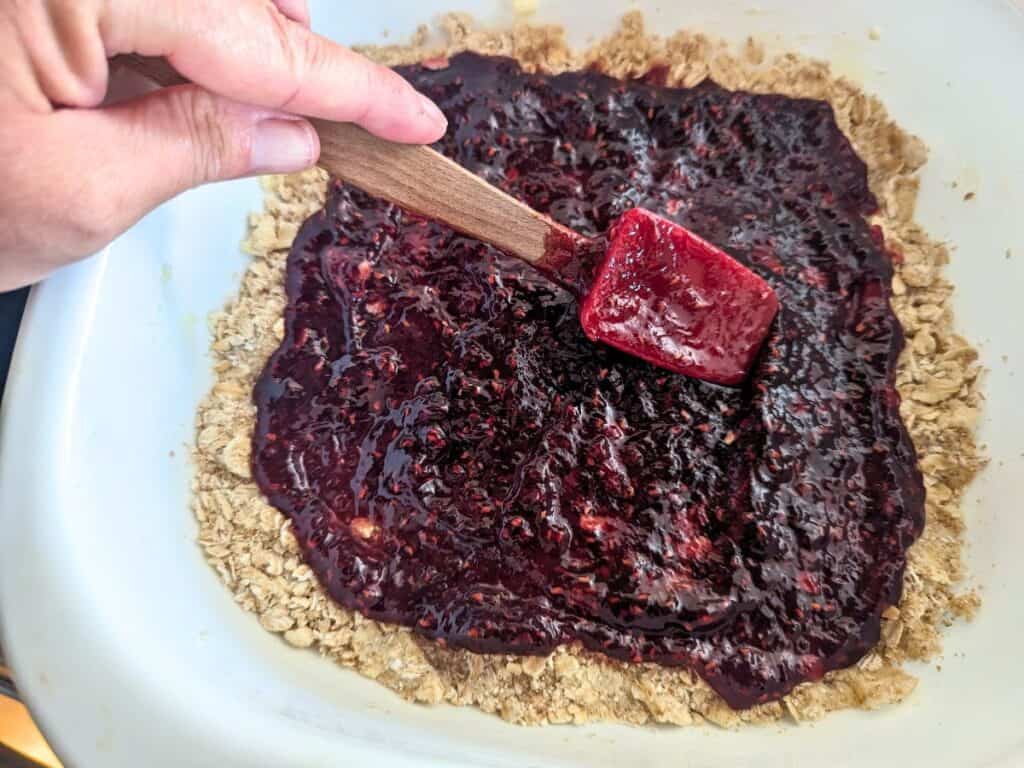 Image shows show someone Spreading jam with a spatula.
