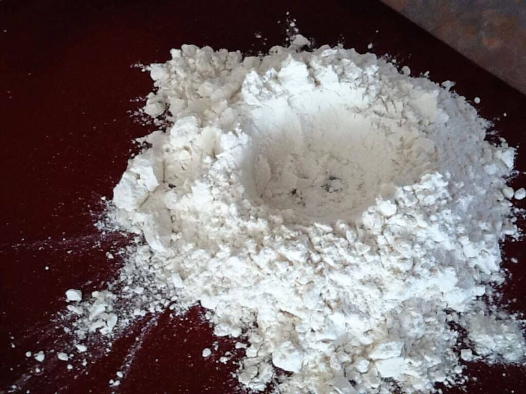 Image shows making a well in a heap of flour.