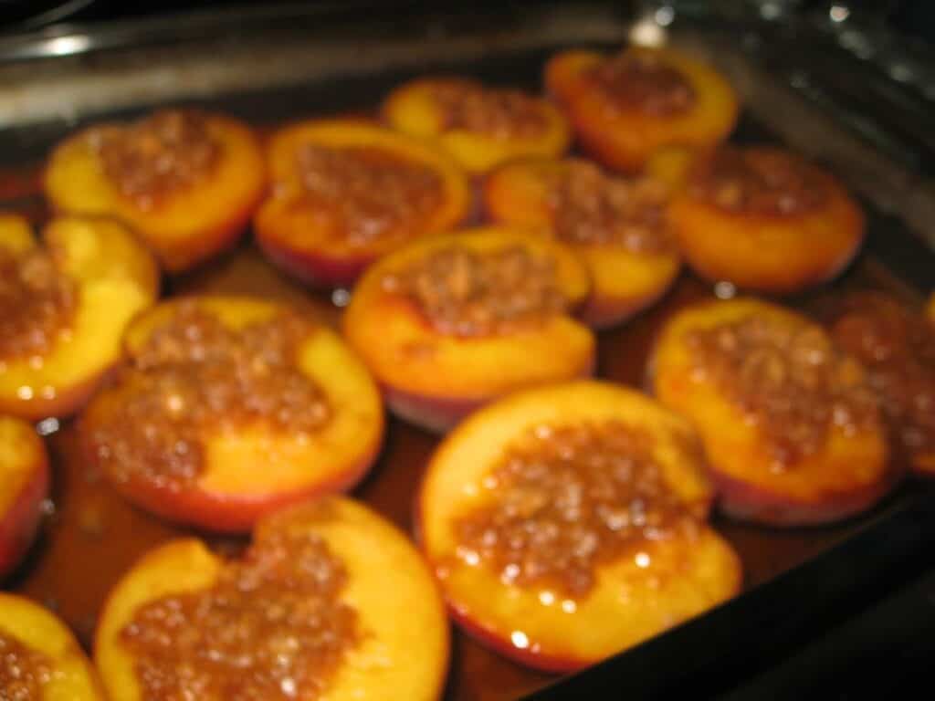 Image shows baked peaches on a glass baking dish.