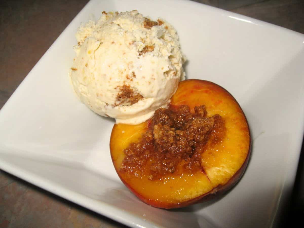 Image shows baked peaches with ice cream on a serving plate.