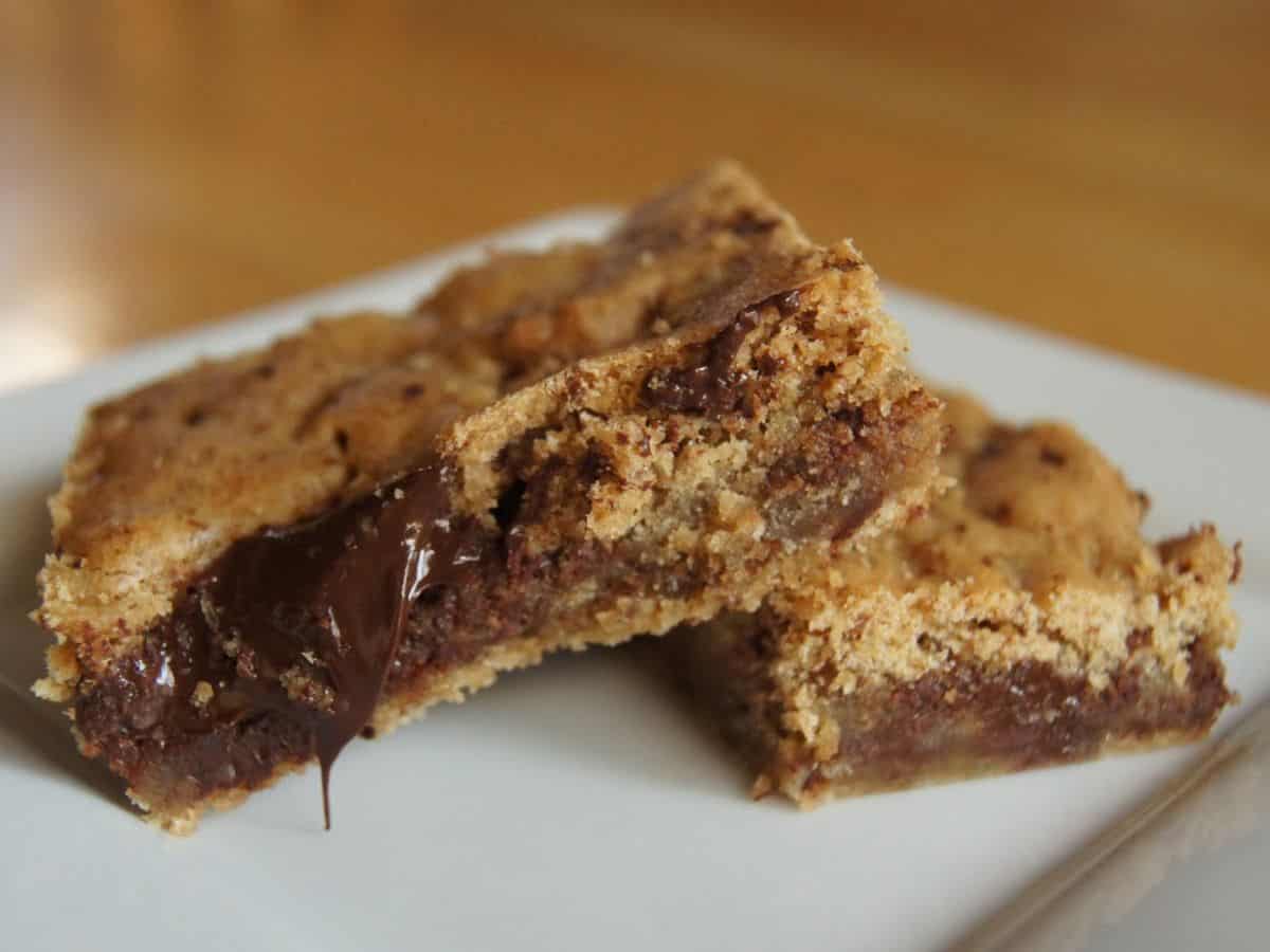 Image shows Two butterscotch brownies with melted chocolate filling on a white plate, close-up view.