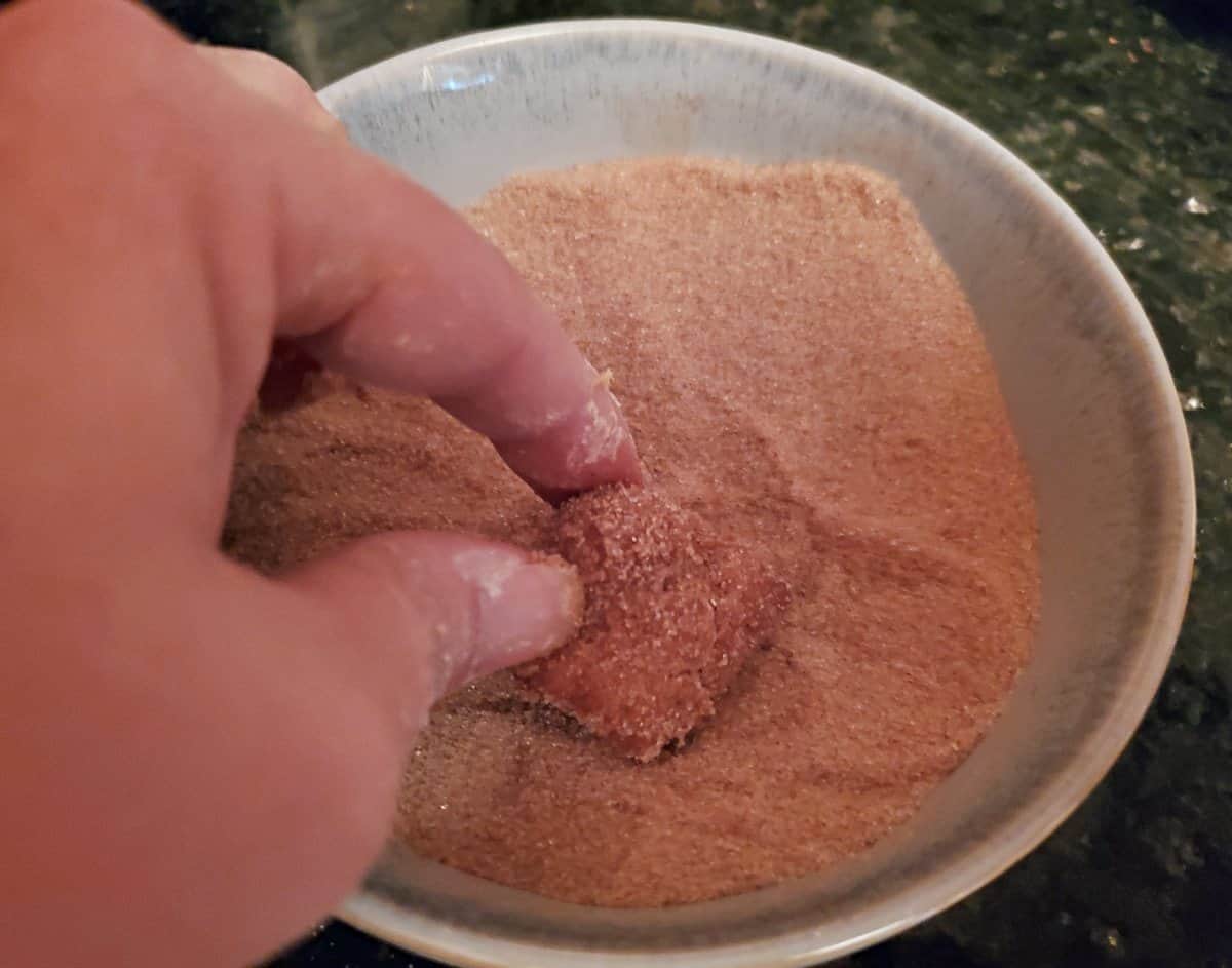 Rolling still hot donut holes in cinnamon sugar.