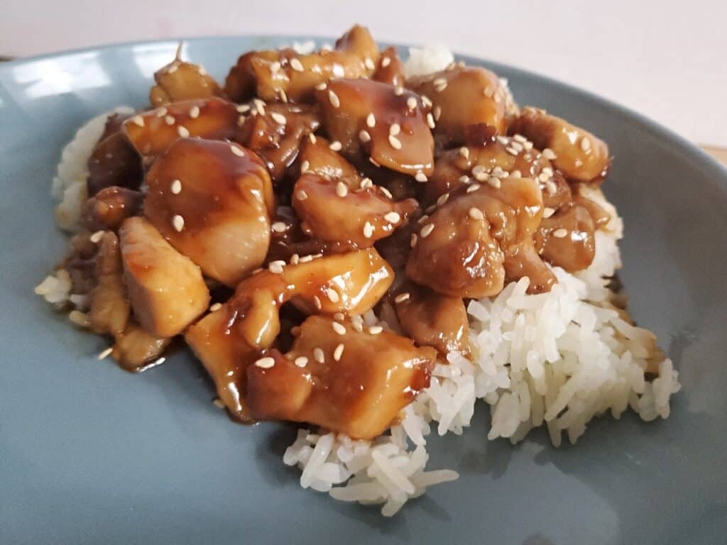 Close up of honey glazed chicken and rice with sesame seeds.