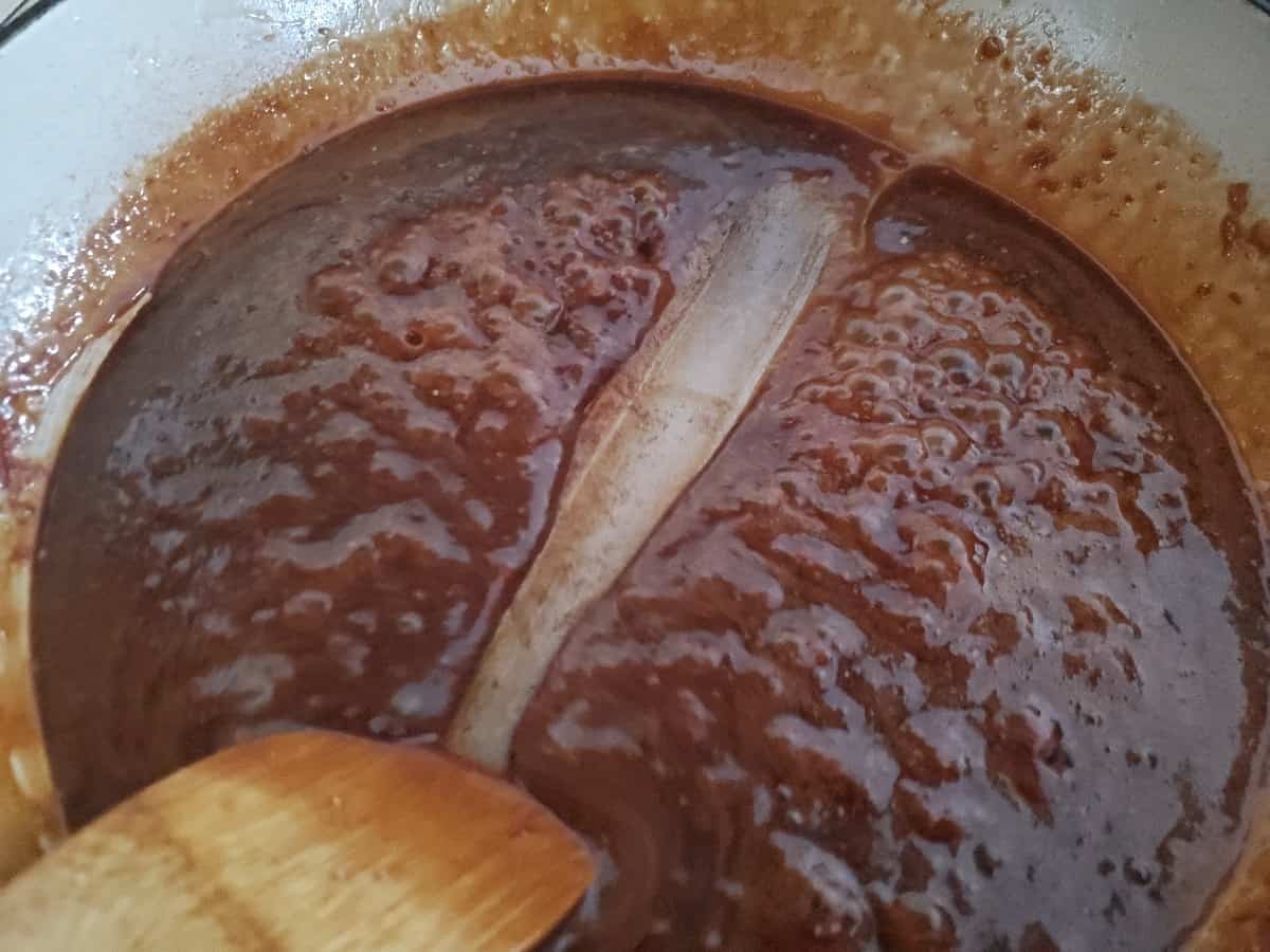 Wooden spoon testing sauce for thickness by running through the middle.