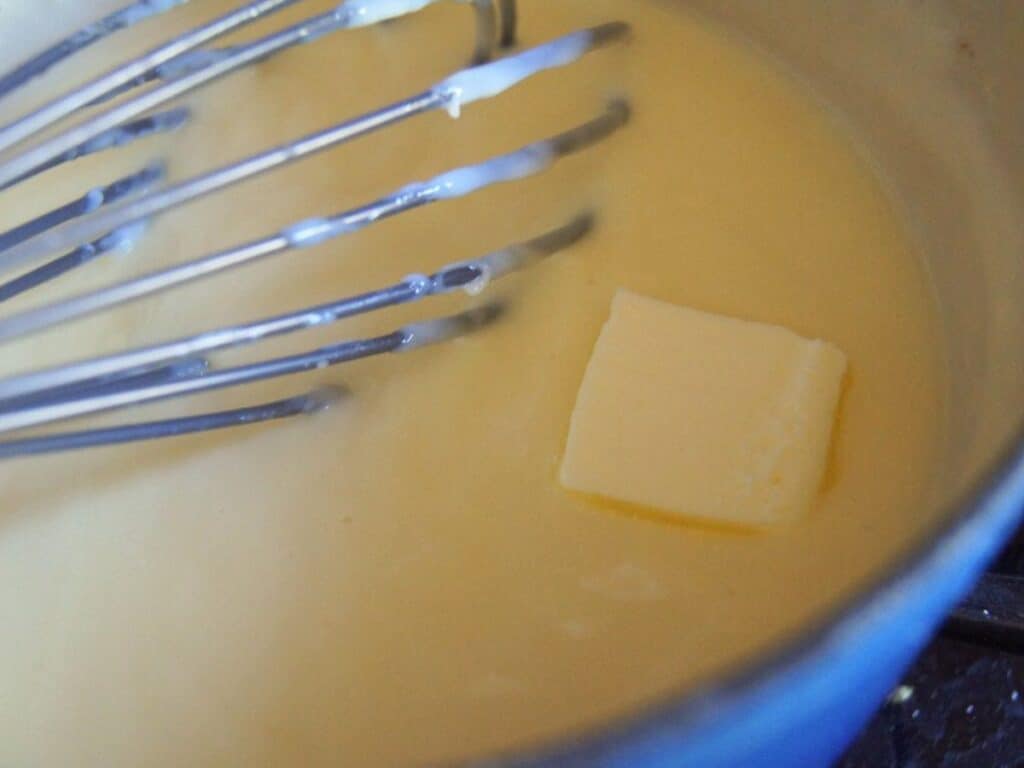 Image shows adding butter to the almost done vanilla pudding.