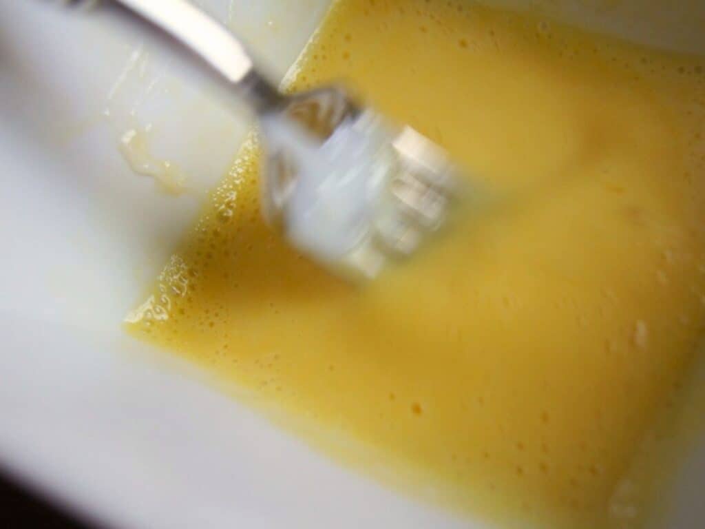Image shows tempering the eggs for homemade vanilla pudding.