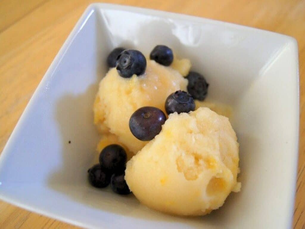 Image shows peach coconut milk ice cream in a bowl.