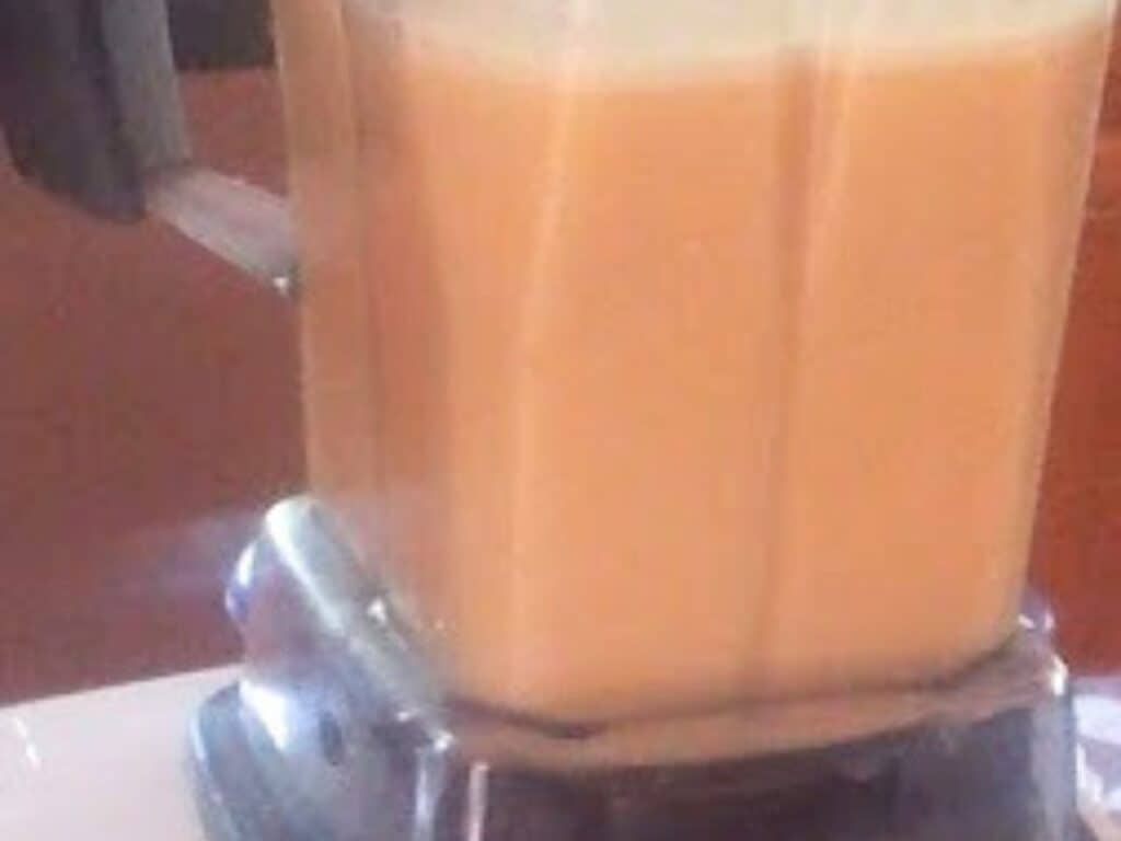 Image shows peach coconut milk ice cream in blender.