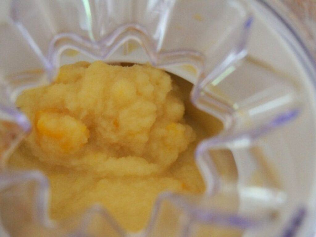 Image shows peach coconut milk ice cream in machine churned.