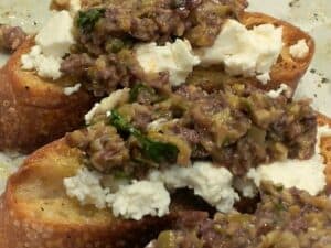 Image shows goat cheese and tapenade crostini.