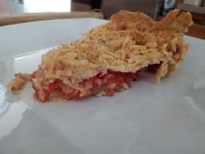 Slice of tomato tart sitting on a white plate.