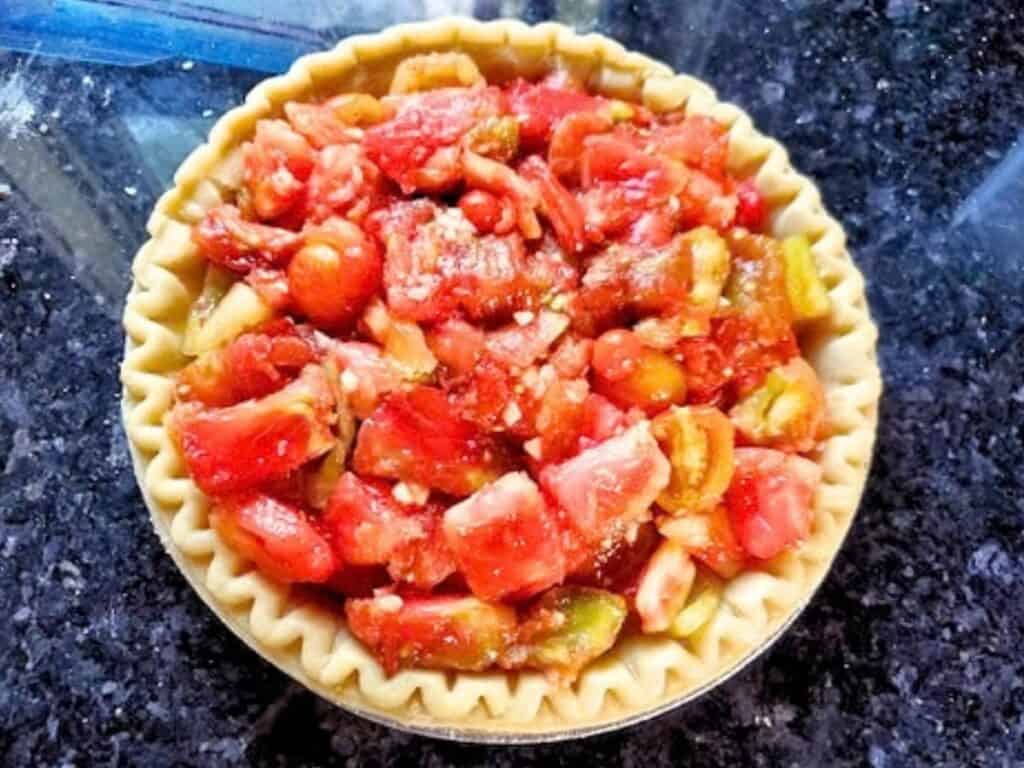 Unbaked pie crust filled with chopped tomatoes.
