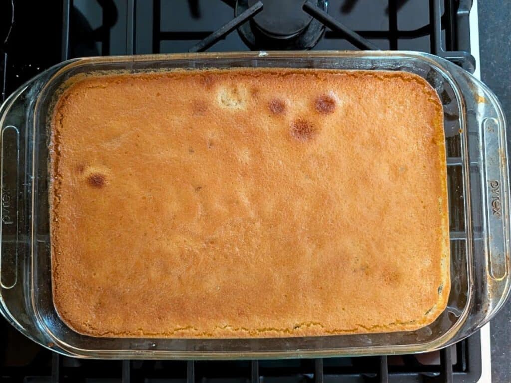 A rectangular glass baking dish with golden-brown baked lemonade cornbread, shown on a black stovetop.