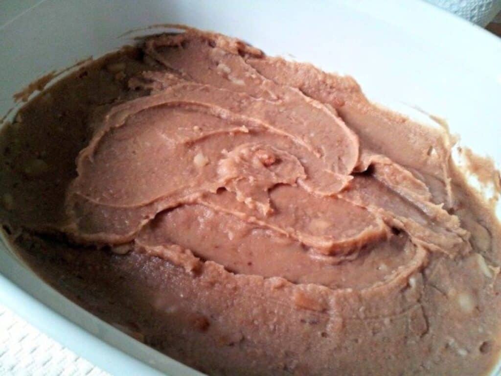 Image shows refried bean base in a container.