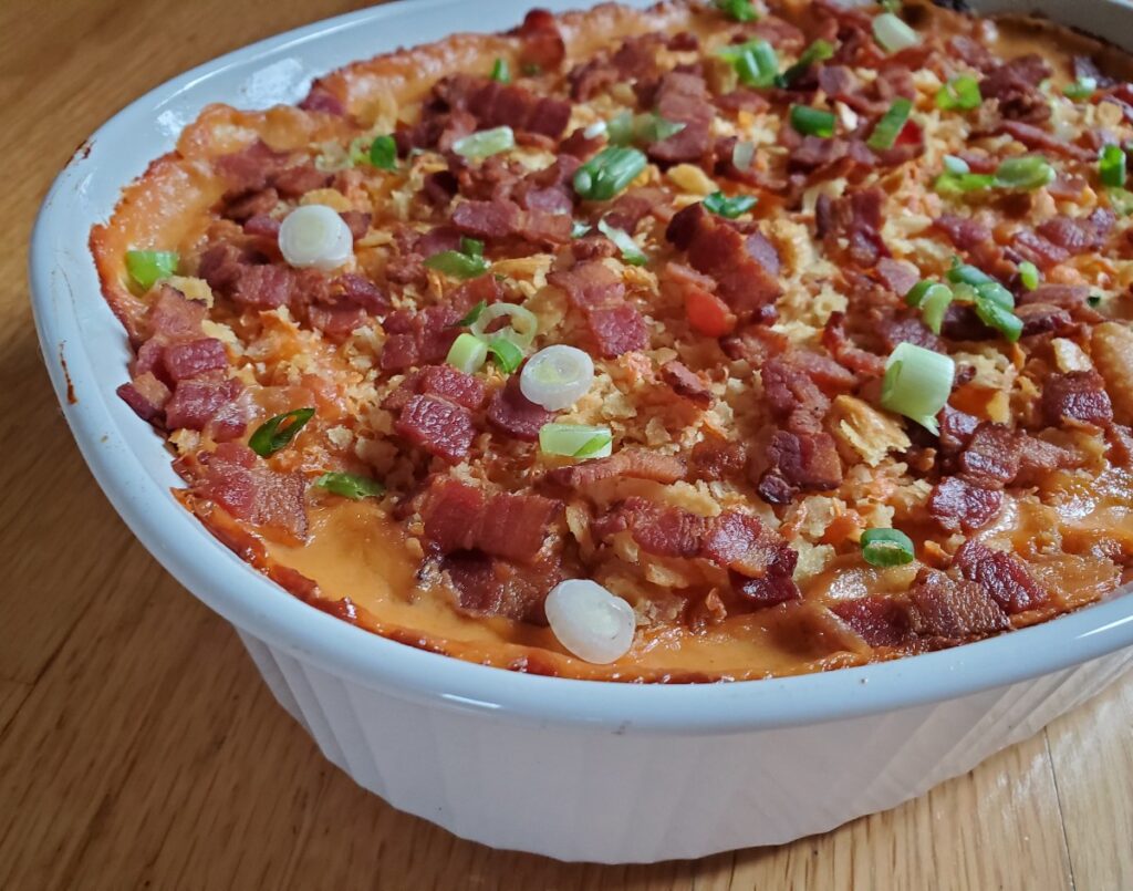 Closeup of corn casserole topped with bacon and green onion.