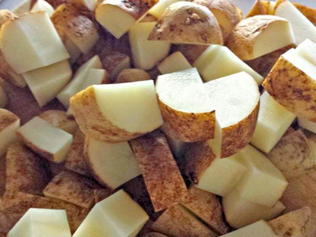 Chopped raw potatoes with skins on, cut into uneven chunks and piled together.