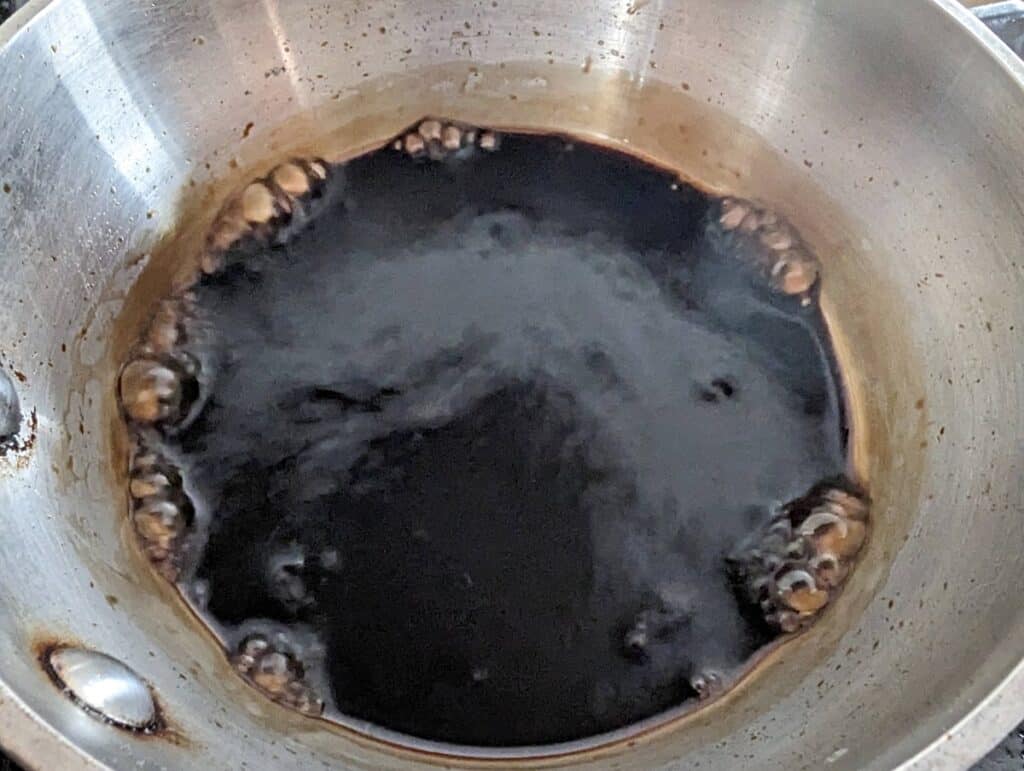 Overhead shot of balsamic vinegar boiling in a silver pot.