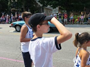 Boy in a white shirt giving a Boy Scout salute.