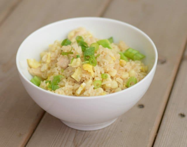 Images shows a white Bowl of chicken fried rice.
