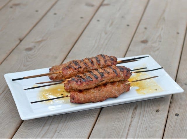Image shows kefta kebabs stacked on a white tray.