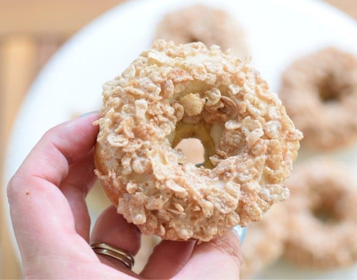 Image shows a Cereal topped donut held over more.