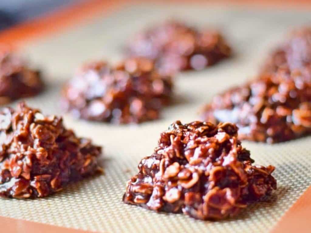 Close-up of several clusters of Nutella no bake cookies set on a silicone baking mat, ready to cool and harden.