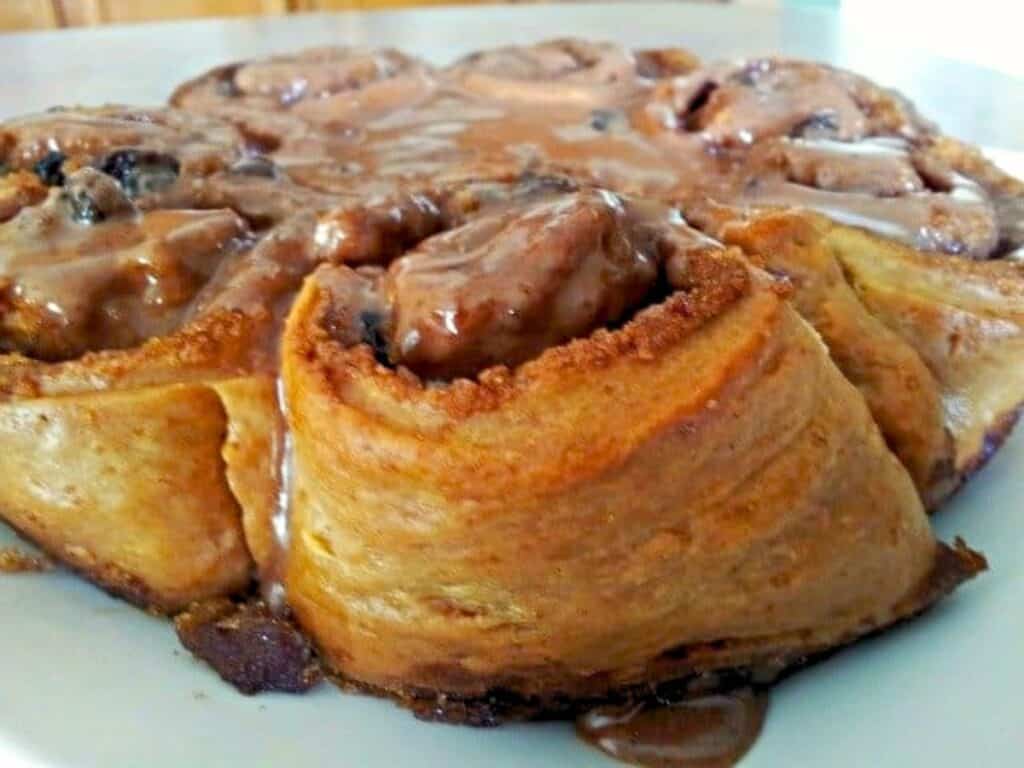 Close-up of no yeast cinnamon rolls on a plate, topped with a light layer of chocolate icing.