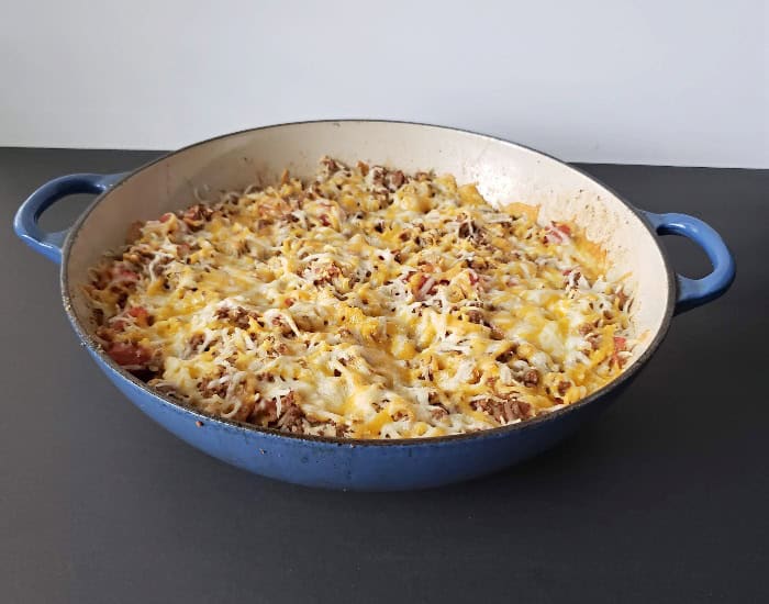 A spoonful of cheesy beef and rice casserole lifted from the skillet.