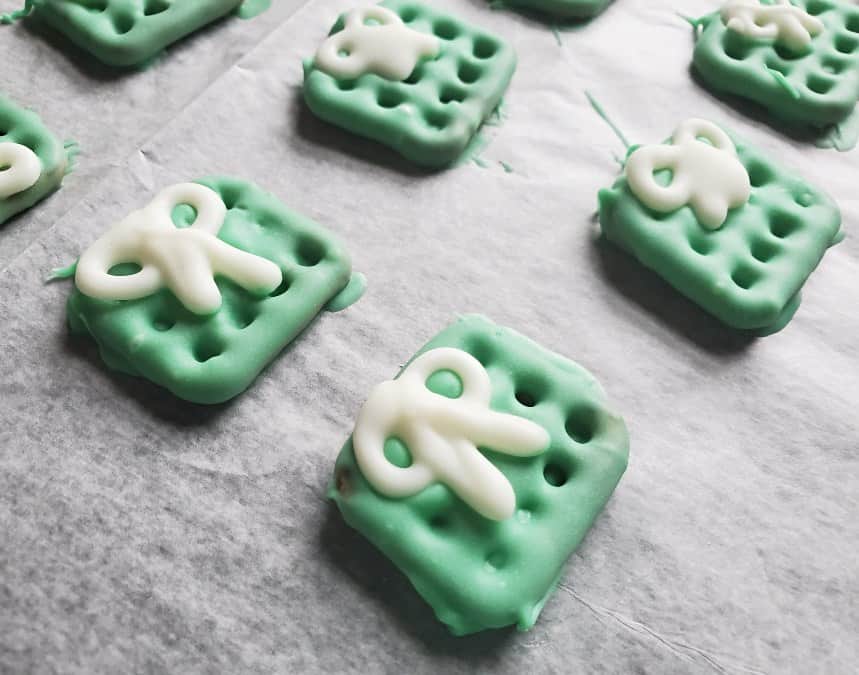 Chocolate covered christmas pretzel presents on wax paper