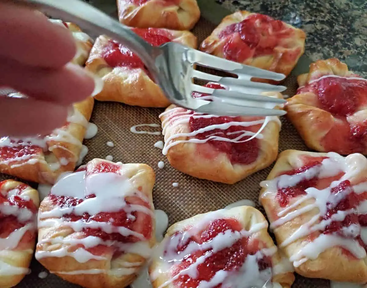 Drizzling strawberry danishes with icing.