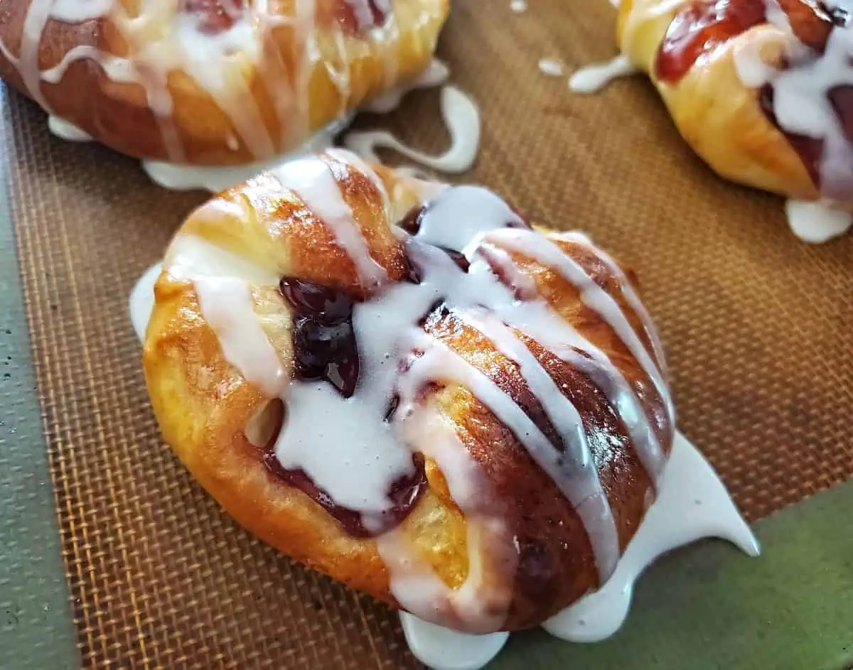 Silpat with three crescent roll danishes.