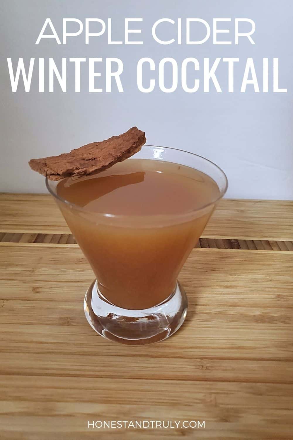 Cocktail glass of cider with cinnamon stick on top and text Apple Cider Winter Cocktail.