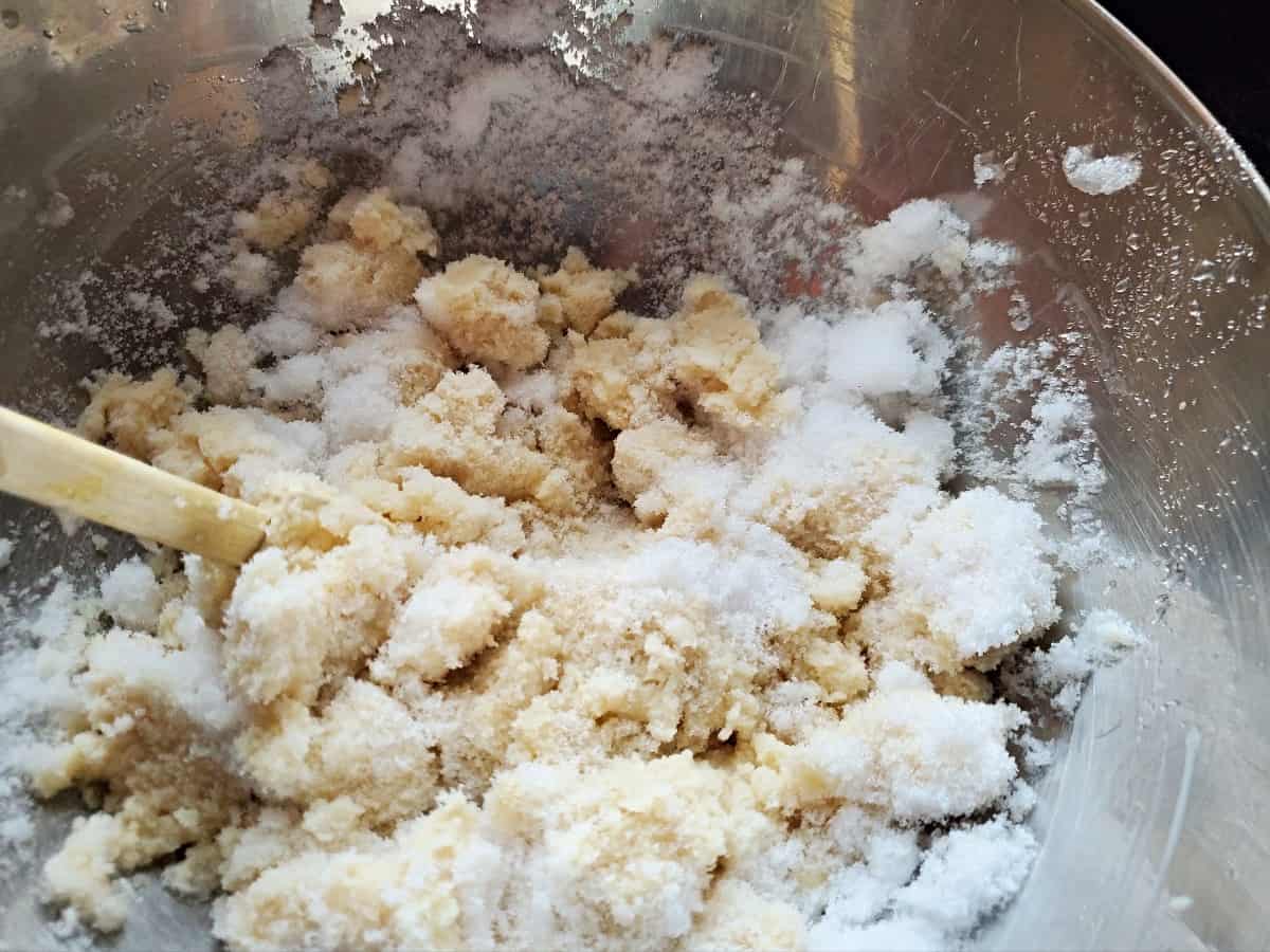 Stirring snow into brown sugar snow cream in a silver bowl.