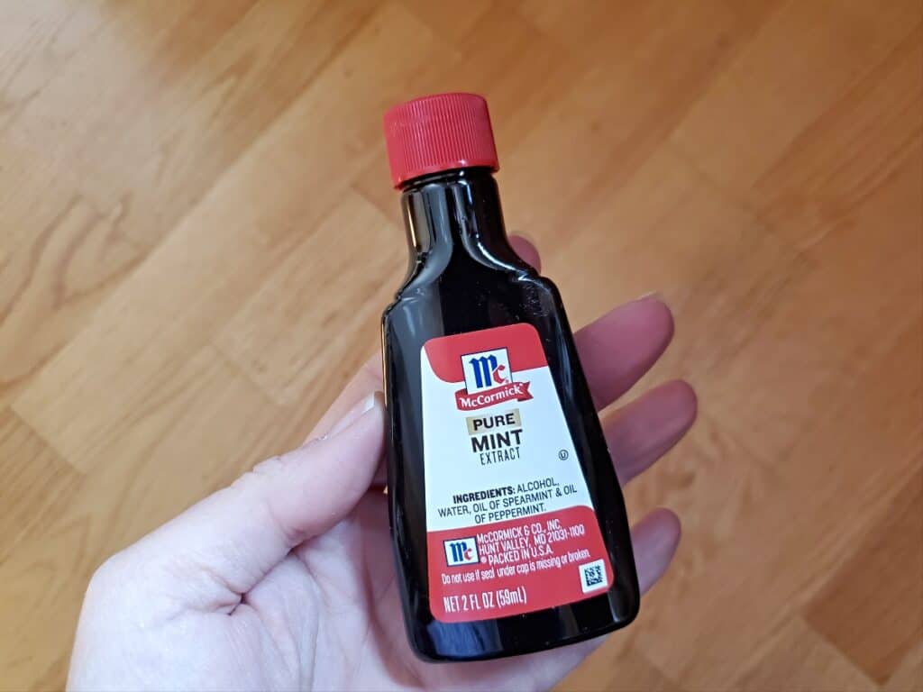 Hand holding a bottle of pure mint extract.