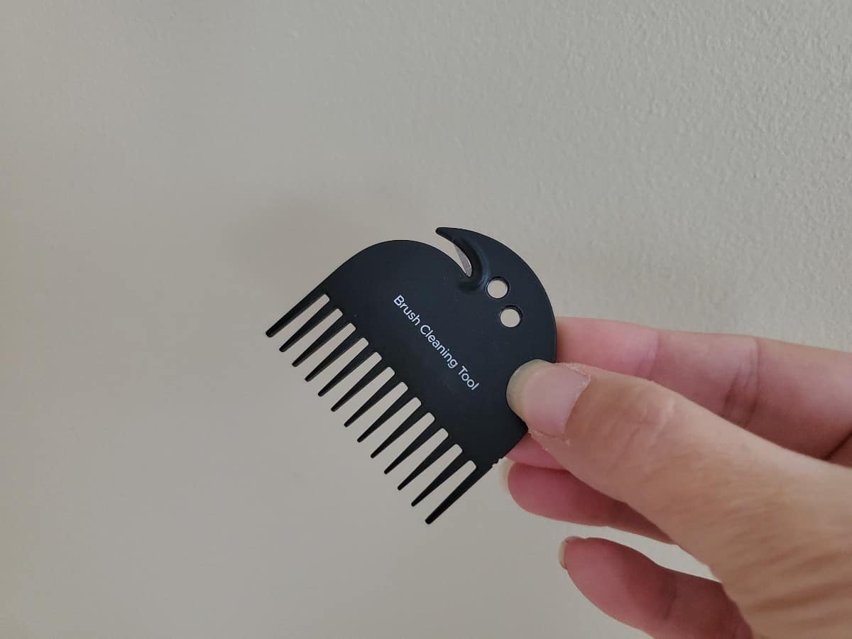Hand holding a neato D10 brush cleaning tool.