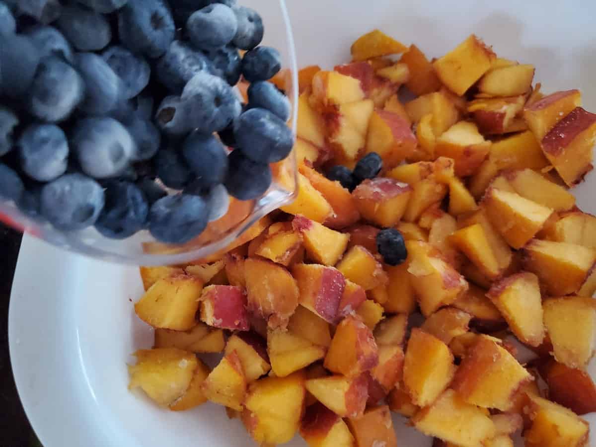 Adding blueberries on top of peaches.