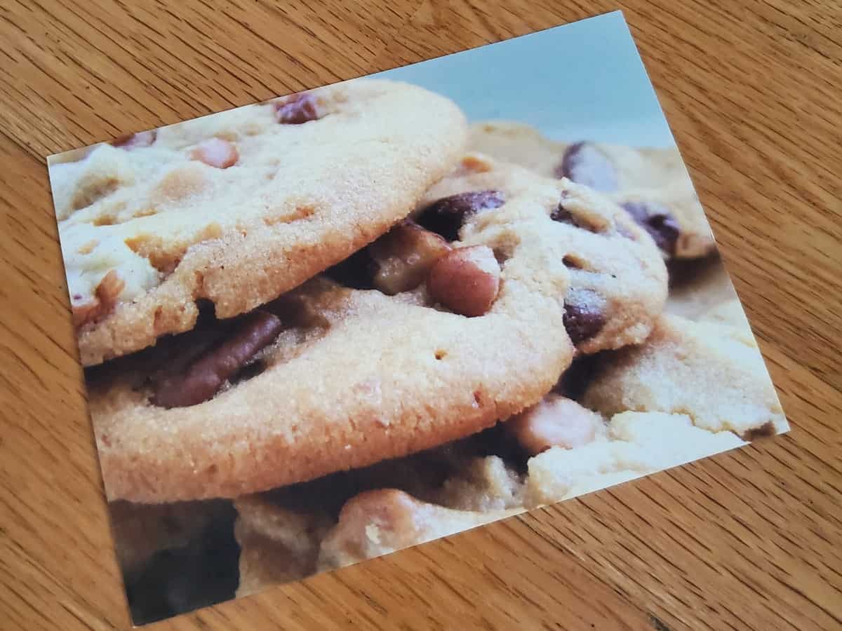 Image of a postcard with three chocolate chip cookies stacked on it.