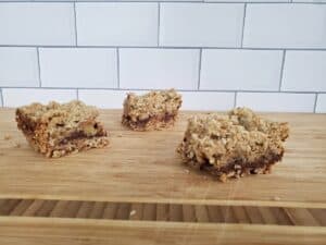 Three chocolate caramel bars sitting on a wooden board.