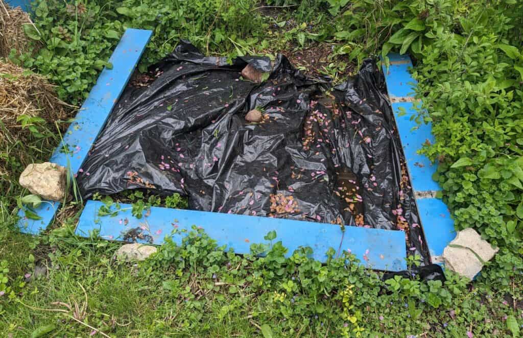 Black plastic weighted down on a garden plot.
