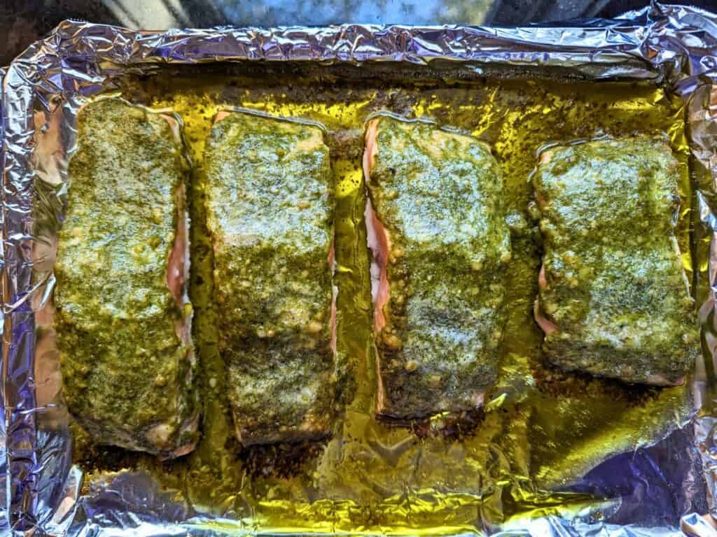 Image shows an Overhead of pesto salmon on a baking sheet.