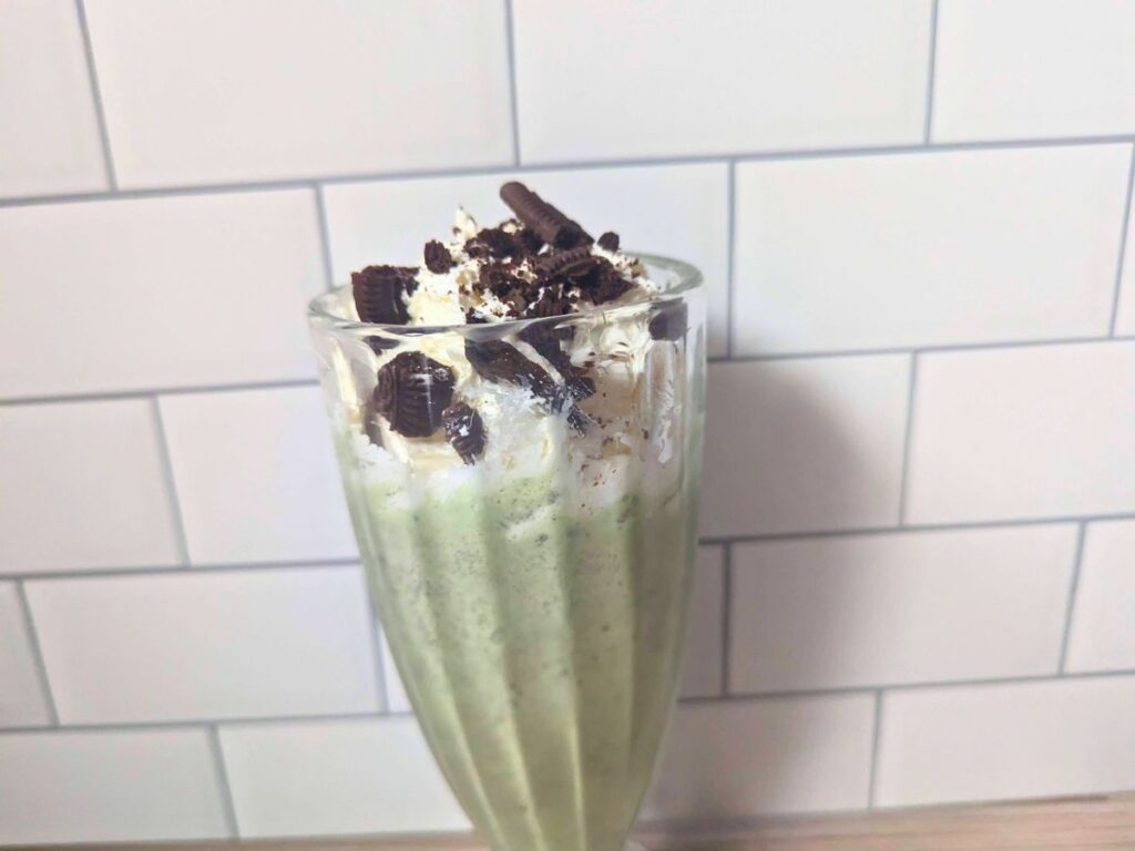 Image shows a Closeup of a peppermint oreo shake in a glass.