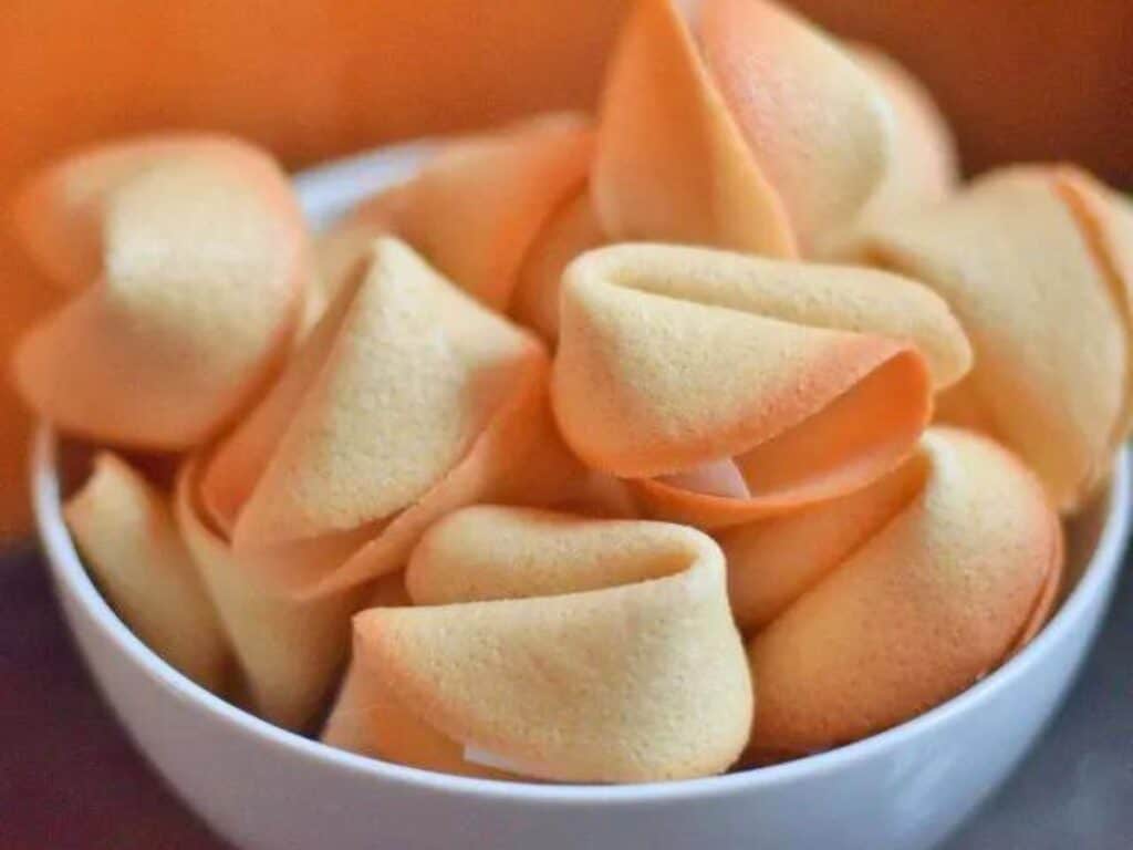 Image shows a bowl full of homemade fortune cookies,