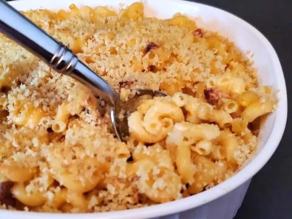 Image shows baked and served in a bowl mac and cheese.