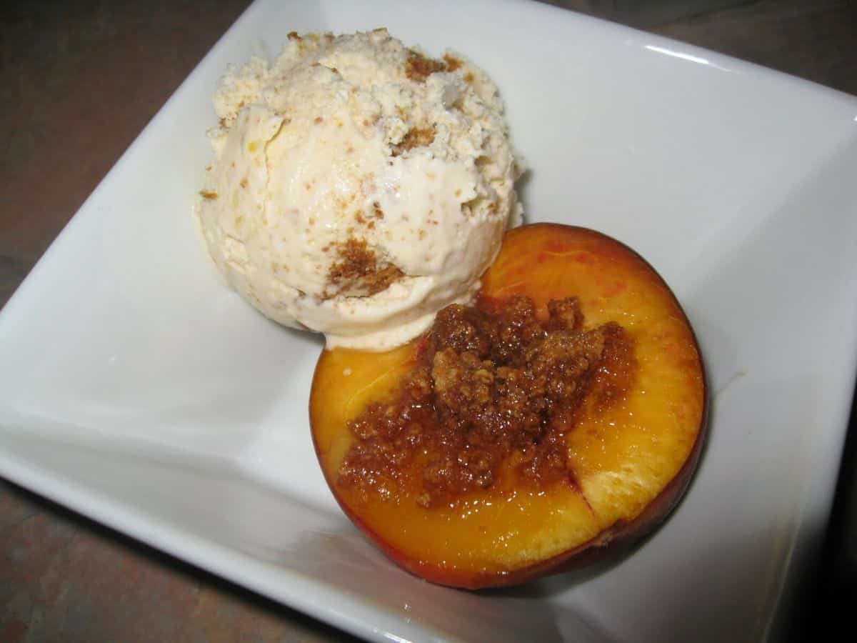 Image shows A baked peach with a scoop of ice cream.