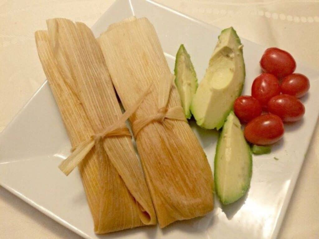 Image shows chicken tamales plated and served.