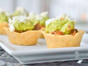 Image shows crockpot Mexican beef in masa cups on a serving plate.