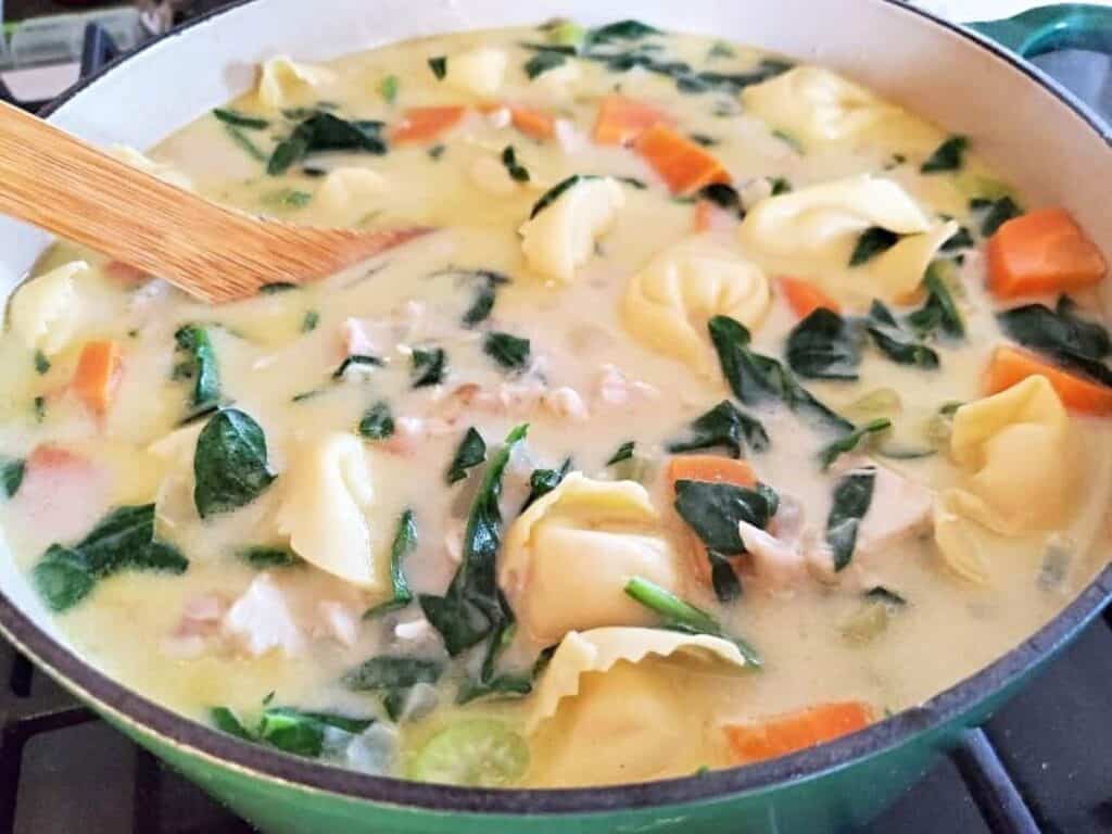 Image shows delicious and creamy chicken tortellini soup in a pot.