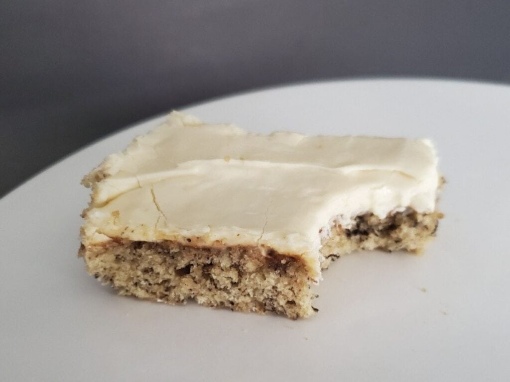 Image shows delicious bite of frosted banana bars.
