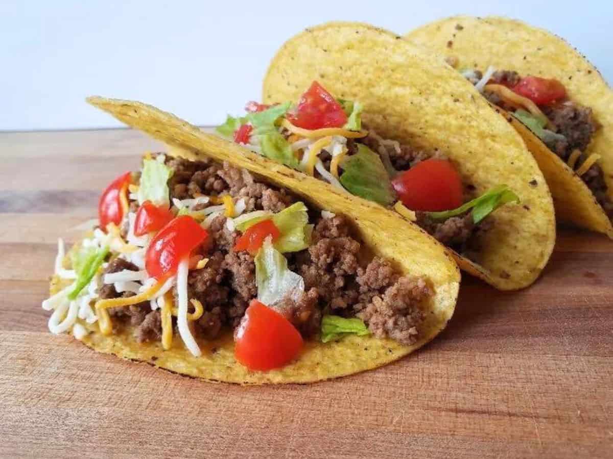 Image shows three honey habanero tacos with corn shells sitting on a wooden board.